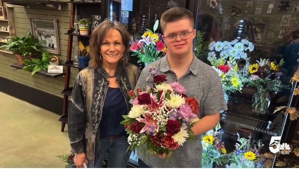 Flower shop owner, DeNyse White, and Quentin Avinger pose for the camera.  Quinten is holding a bouquet of flowers that he arranged.